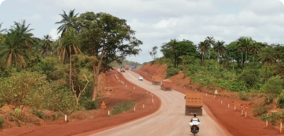 Vehicles travel down a rural dirt road in Africa